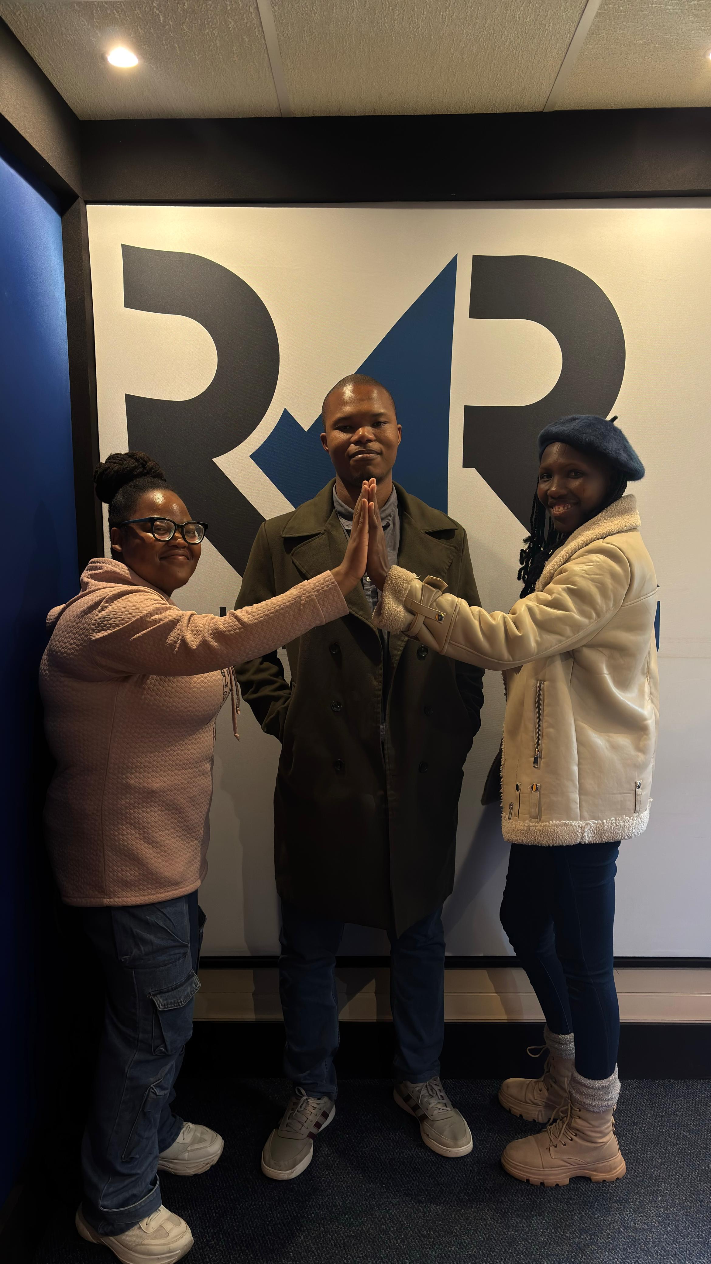 Three Playdate producers in front of the RMR logo
