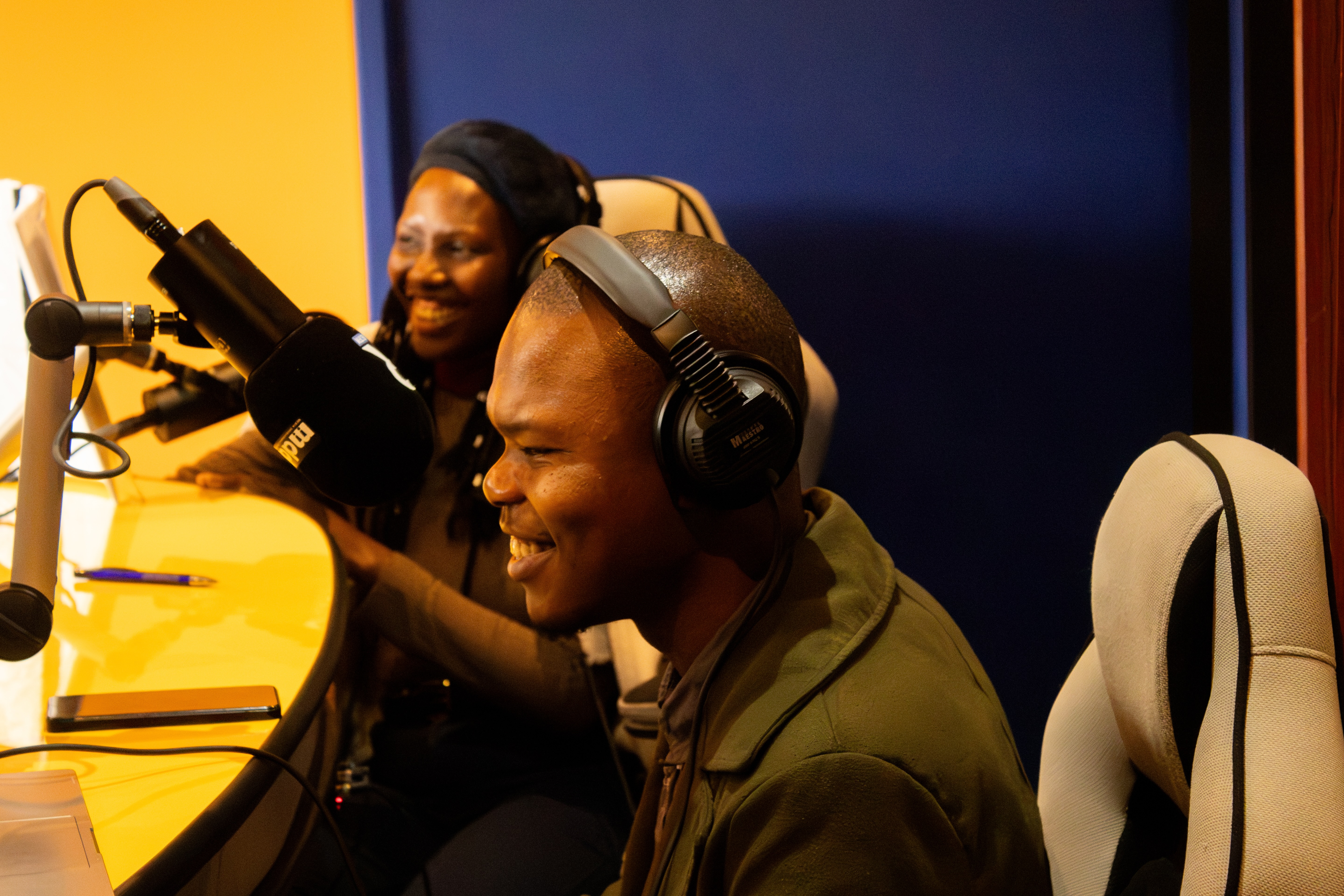 Two hosts laughing at the microphone